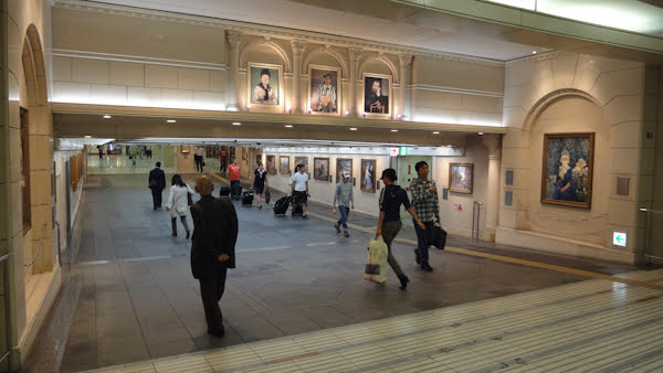 an indoor walkway looking like stone masonry decorated with reproductions of paintings